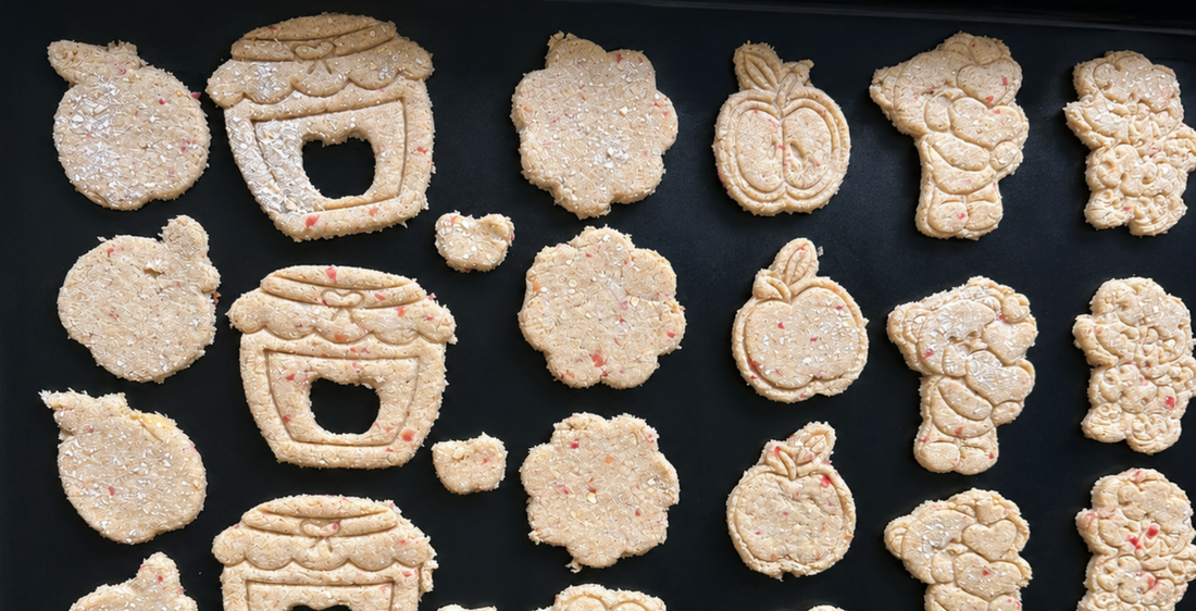 Tray of apple, honey-pot and flower shaped dog cookies freshly cut at Pooches Pantry