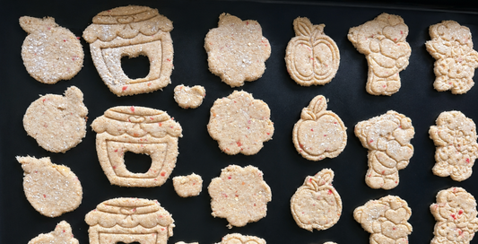 Tray of apple, honey-pot and flower shaped dog cookies freshly cut at Pooches Pantry