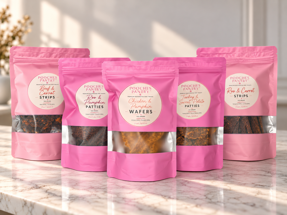 The Whole Pantry: all five Pooches Pantry treat bags on a marble bench, with Chicken & Pumpkin Wafers in front